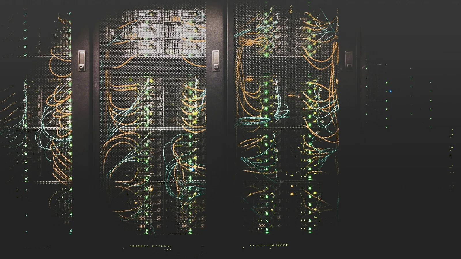 Rows of data centre server racks with orange and blue fibre patch cables
