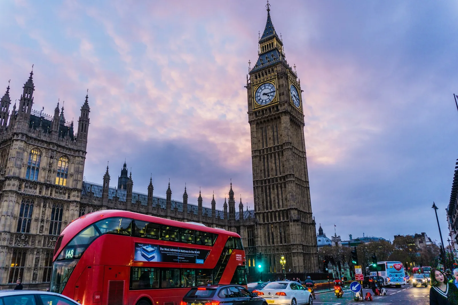 The Palace of Westminster and Big Ben at dusk, with a red London bus passing